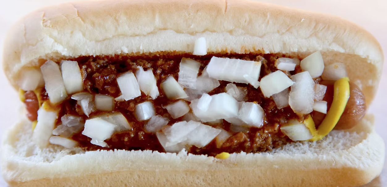 Close-up of a chili dog with onions and mustard